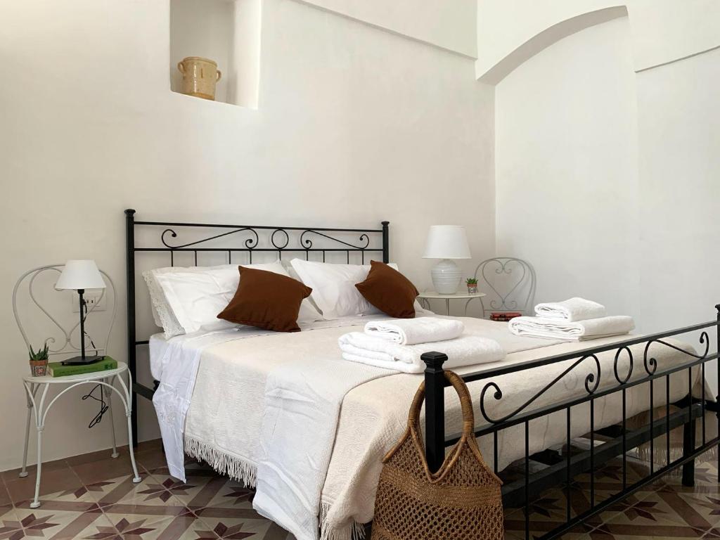 a bedroom with a bed with white sheets and brown pillows at Trullo Aprìco in Alberobello