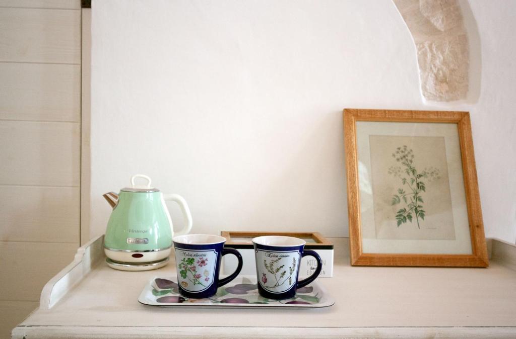 two coffee mugs on a shelf with a picture at Trullo Aprìco in Alberobello