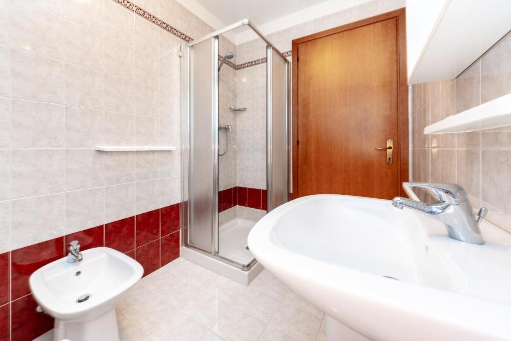 La salle de bains est pourvue d'un lavabo, de toilettes et d'une douche. dans l'établissement Appartamenti Lignano Sabbiadoro - Villa Ammiraglia, à Lignano Sabbiadoro