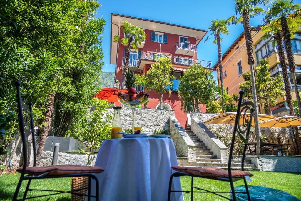a table with two chairs and a building in the background at Villa Muralto Rooms & Garden in Locarno