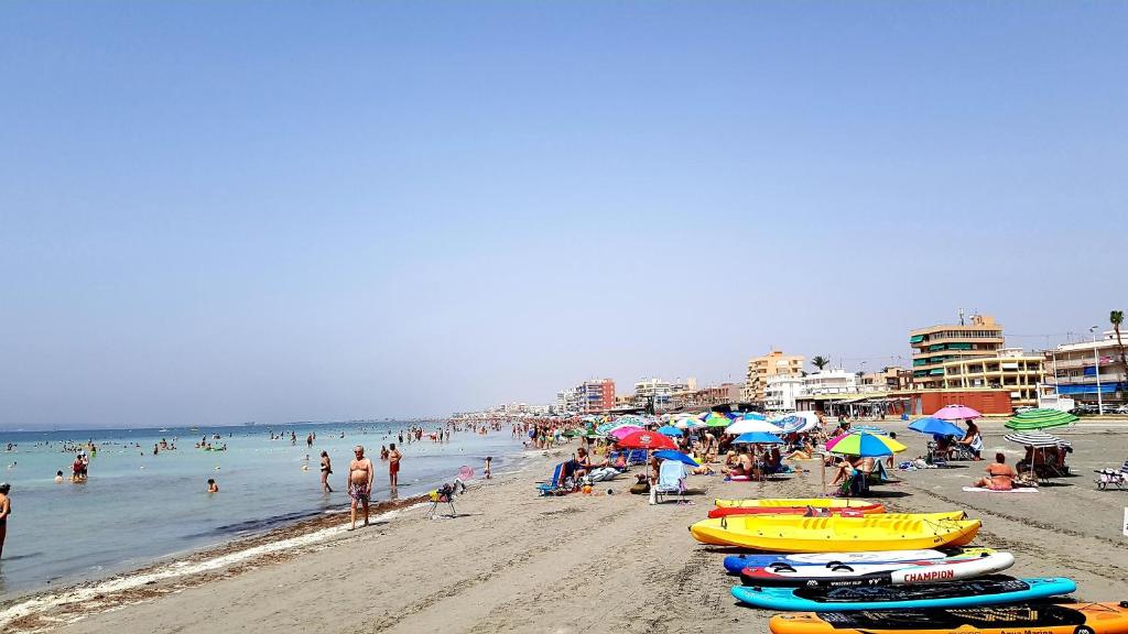 - une plage avec des personnes, des parasols et des personnes dans l'eau dans l'établissement Apartamento con tres dormitorios Vista Mar, à Santa Pola