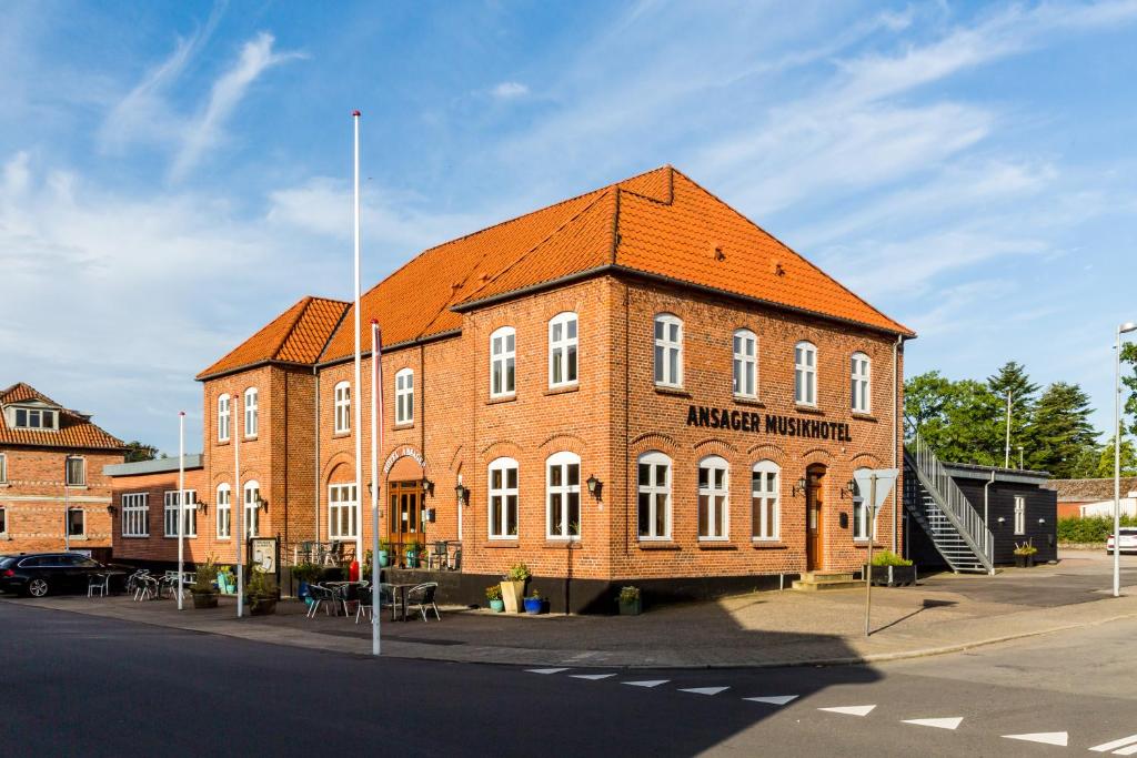un grand bâtiment en briques avec un toit orange dans l'établissement Ansager Hotel og Hytteby, à Ansager