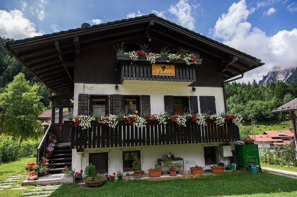 uma casa com vasos de flores e uma varanda em B&B La Genzianella em Perarolo di Cadore