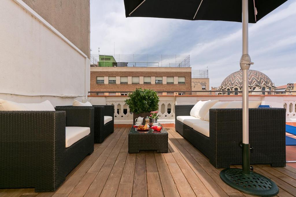 a patio with couches and an umbrella on a roof at Bcn Paseo De Gracia Rocamora Apartment in Barcelona