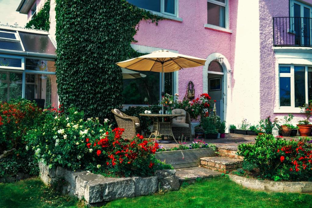 a patio with an umbrella and flowers in front of a house at The Sands B&B Rostrevor in Rostrevor