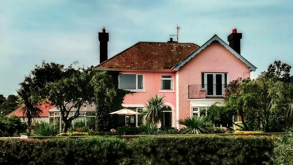 uma casa cor-de-rosa com um telhado vermelho em The Sands B&B Rostrevor em Rostrevor