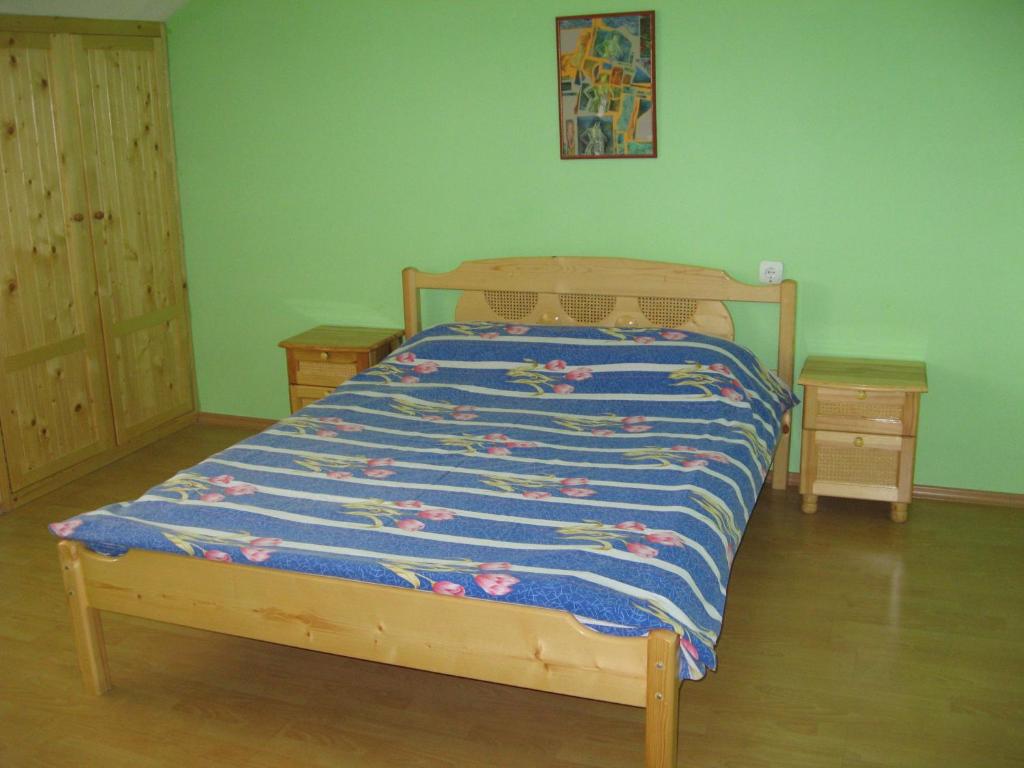 a bedroom with a bed with a blue comforter and two tables at Кристи in Shumen