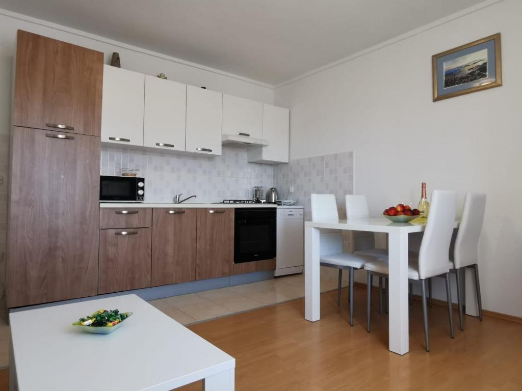 una cocina con armarios blancos y una mesa y sillas blancas. en Apartment Branka Kustura, en Hvar