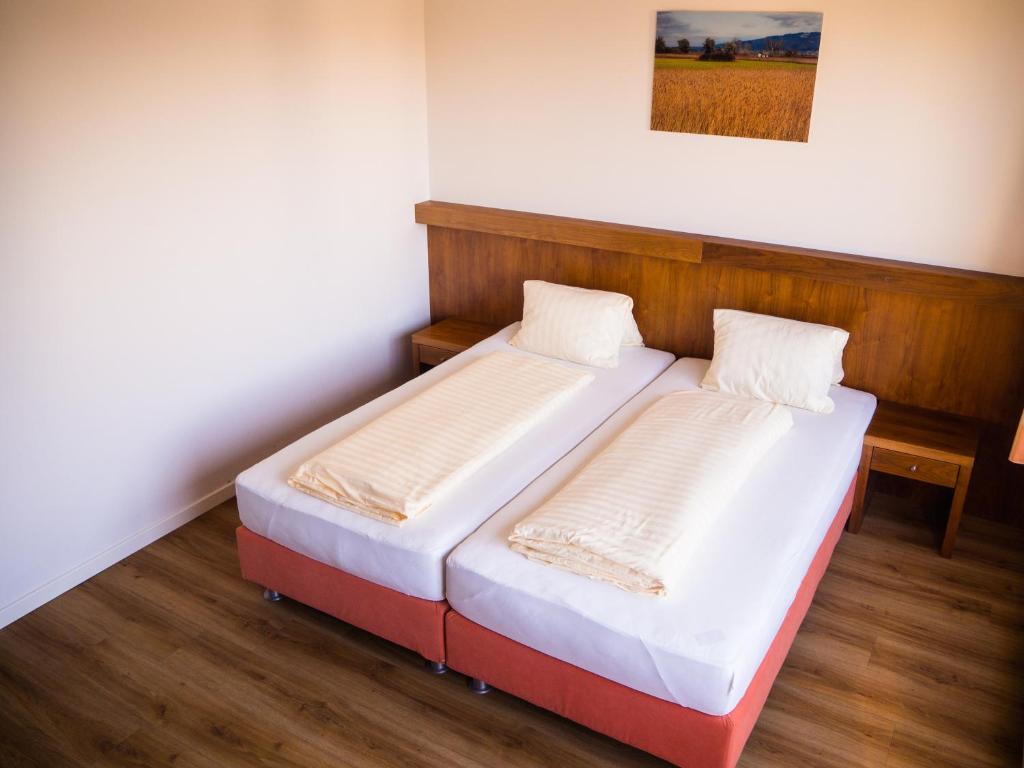 2 łóżka pojedyncze w pokoju z drewnianą podłogą w obiekcie Gasthof Meindl w mieście Lustenau