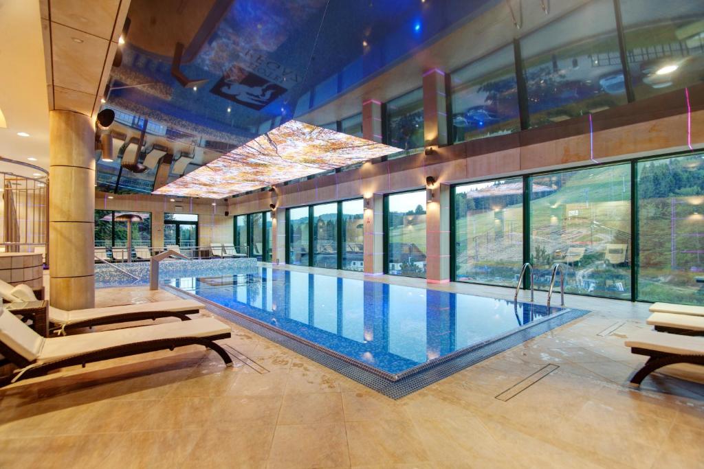 a large swimming pool in a building with windows at Hotel Pegaz in Krynica Zdrój