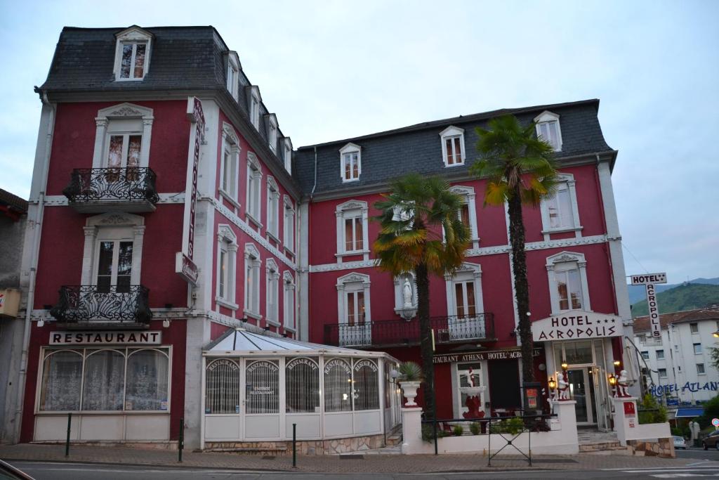 um grande edifício vermelho com uma loja em frente em Hôtel Acropolis em Lourdes