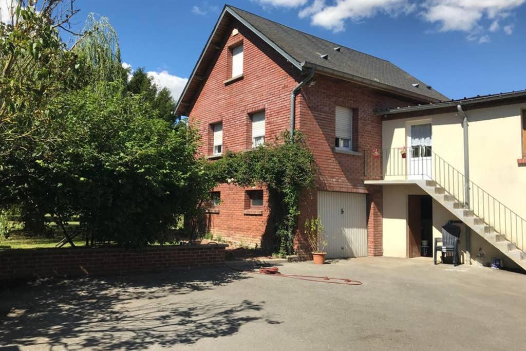 uma casa de tijolos vermelhos com garagem e entrada em Cottage Centulois em Saint-Riquier