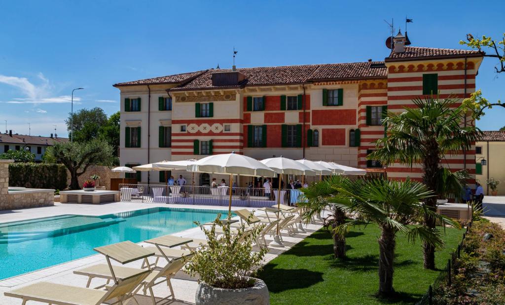 um resort com piscina e cadeiras e um edifício em Boutique Hotel Villa Zoppi - Adults only em Colognola ai Colli
