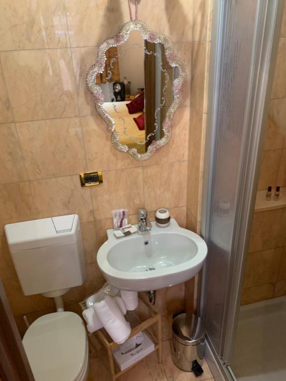 a bathroom with a sink and a toilet and a mirror at Luxury Venetian Rooms in Venice