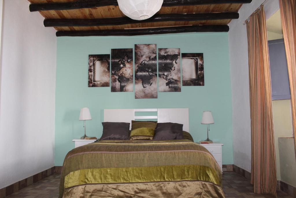 Casa Rural Ventanas a la Sierra في إيغيرا دي لا سييرا: غرفة نوم بها سرير ومصباحين على الحائط