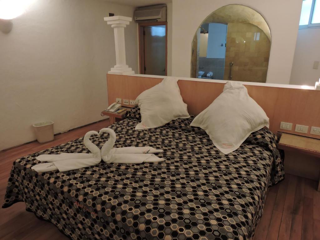 Un dormitorio con una cama con dos zapatos. en Motel Mykonos en Puebla