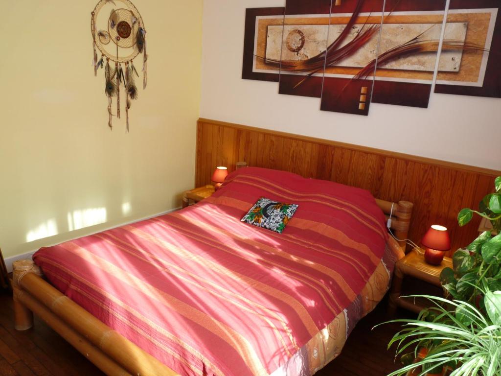 a bedroom with a bed with a red comforter at La Maison des Lys in Chissey-lès-Mâcon