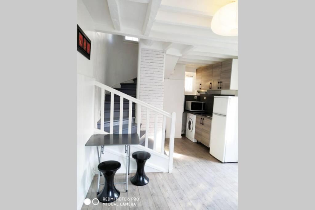 une cuisine avec un escalier et une table dans une pièce dans l'établissement Maison Montfermeilloise entre Paris et Disneyland, à Montfermeil