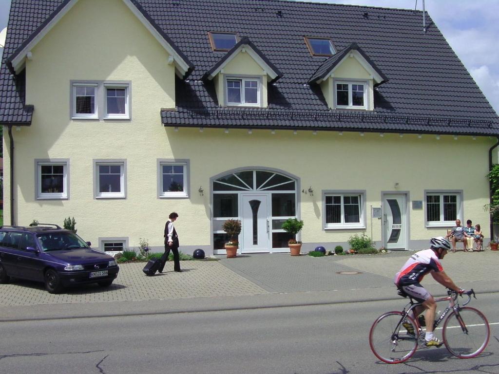 a person riding a bike in front of a house at Kurpension Meßmer in Tengen