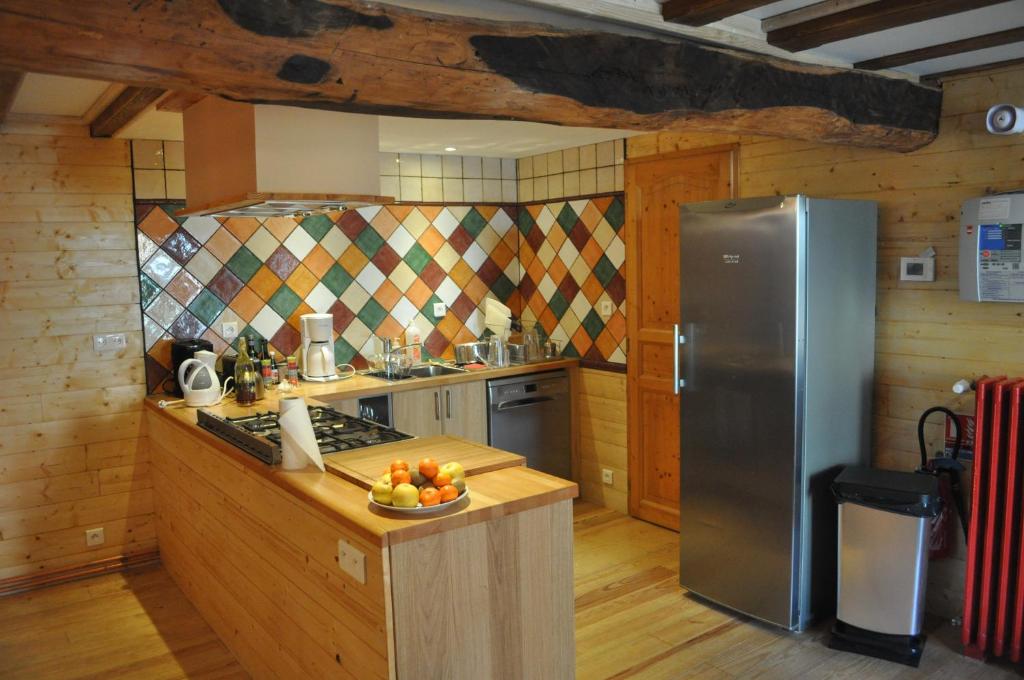 a kitchen with a refrigerator and a bowl of fruit on a counter at Eco Gite La Grange in Fos