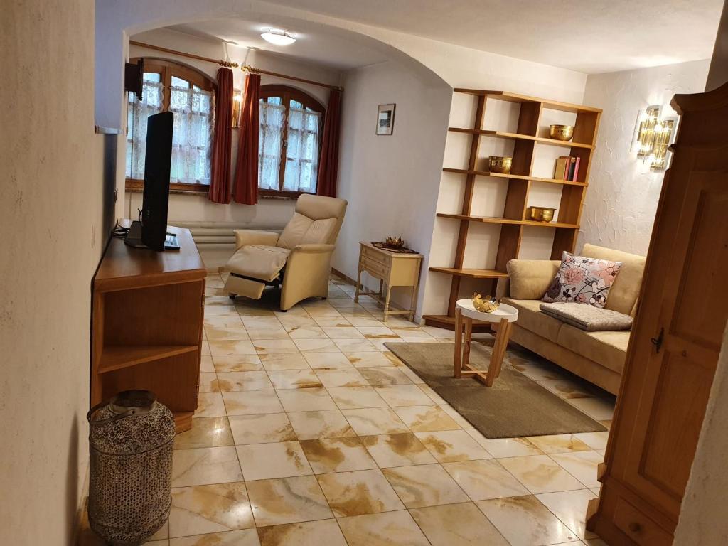 een woonkamer met een bank en een tv bij Bezauberndes Haus für erholsame Ferien im Puschlav in Campascio