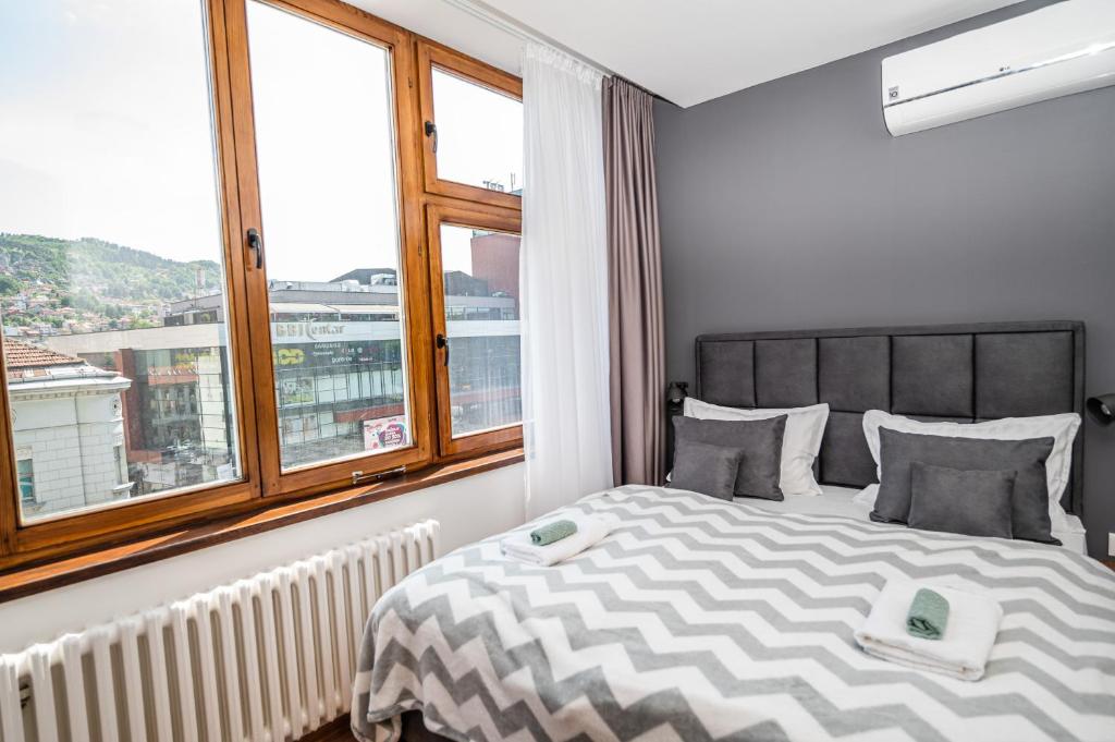 a bedroom with a bed with a large window at Modern and Bright Apartments - Main Street in Sarajevo