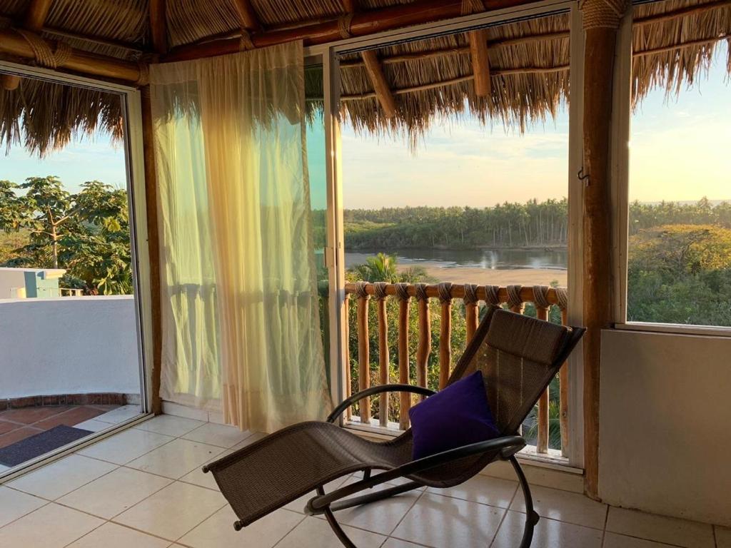 a chair on a porch with a view of the ocean at Casa del Estero playa Platanitos in Compostela