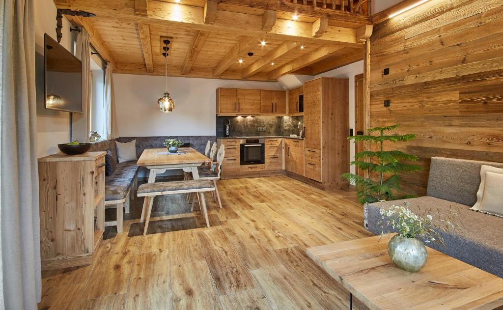 a living room with a table and a kitchen at Chalet Dirndl und Buam in Saalbach-Hinterglemm