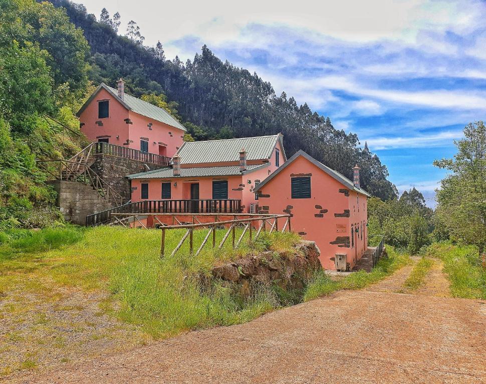 een groot roze huis op een heuvel naast een weg bij Casinhas da Laurissilva in São Vicente