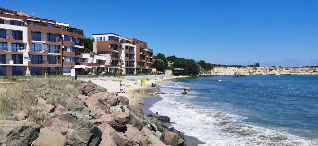 a beach with some rocks and some buildings and the water at Апартаменти и студия в комплекс Акротирия in Nesebar
