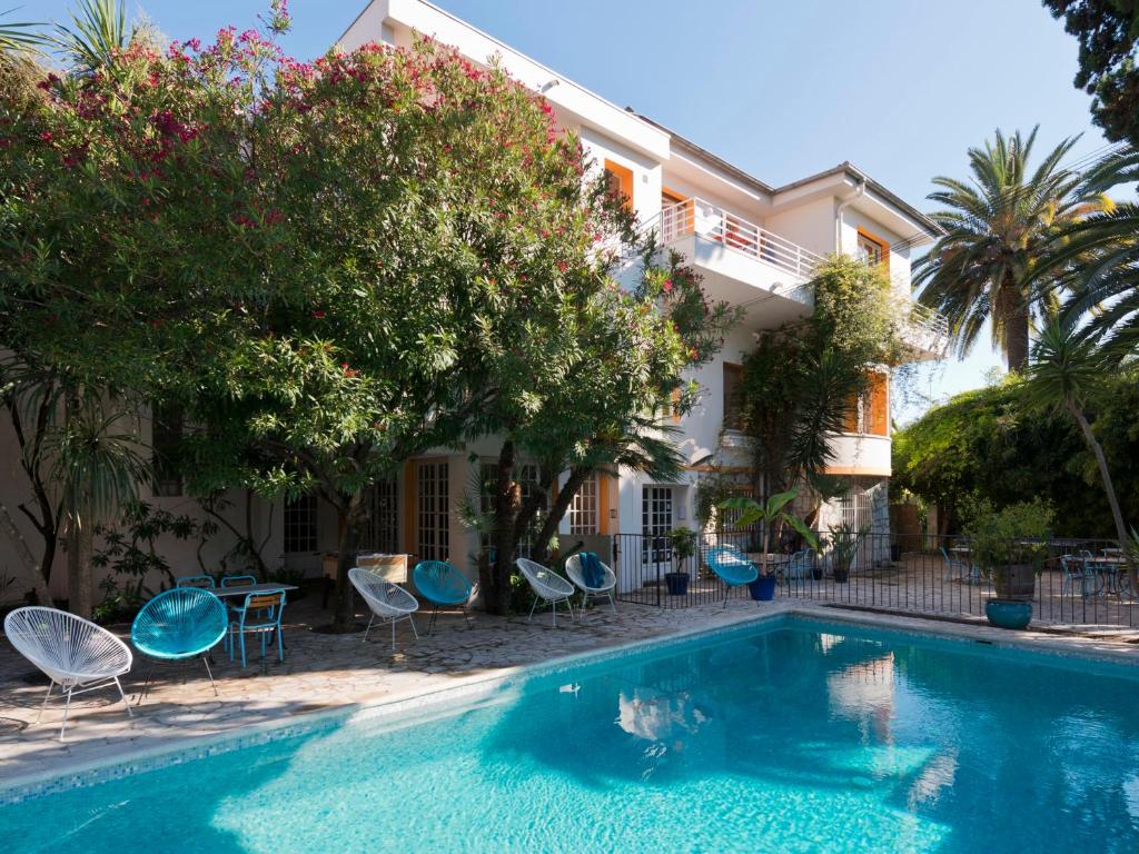a swimming pool with chairs and a building at Le Val Duchesse Hotel & Appartements in Cagnes-sur-Mer