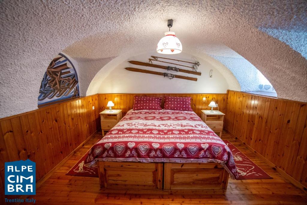 um quarto com uma cama com um edredão vermelho em La stube degli sciatori em Serrada