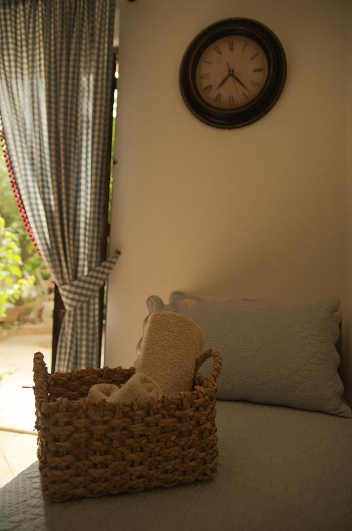 a clock on the wall above a basket on a bed at B&B del Giglio in Cefalù