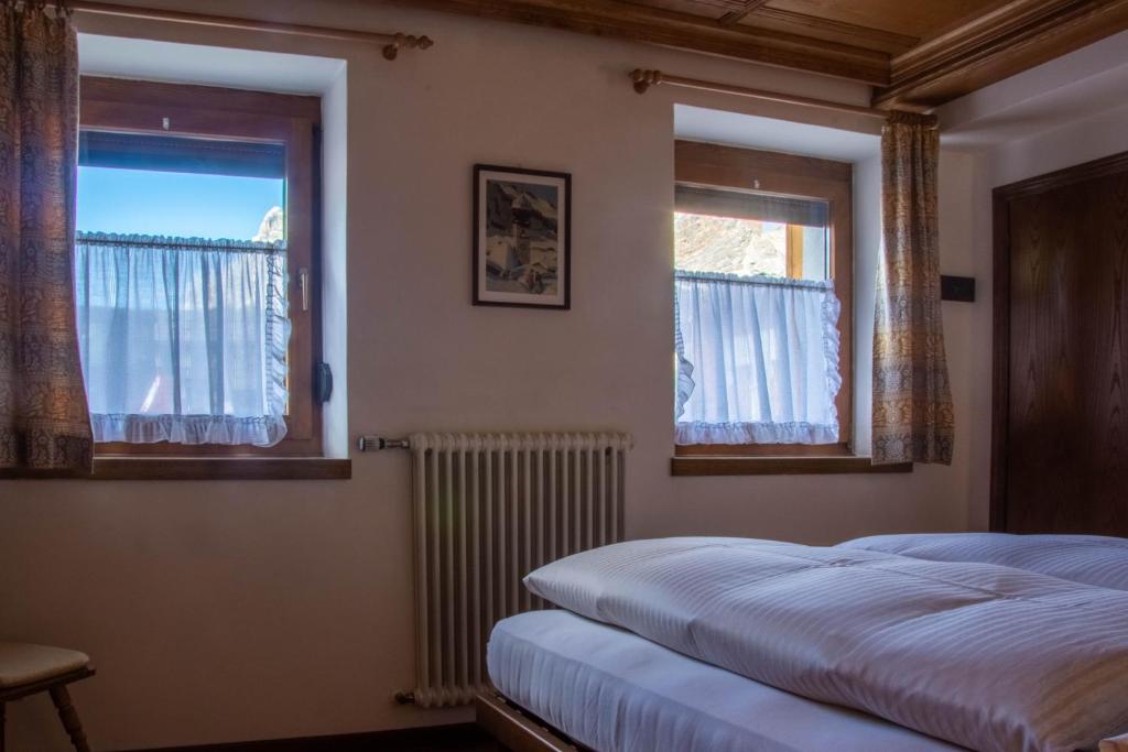 Un dormitorio con dos camas y dos ventanas. en Apartments Ciasa Colz, en La Villa