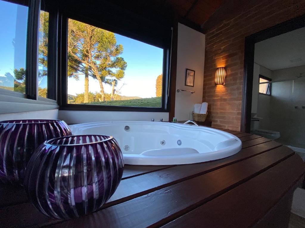 a large tub in a bathroom with a large window at Chalés Cinco Estrelas in Monte Verde