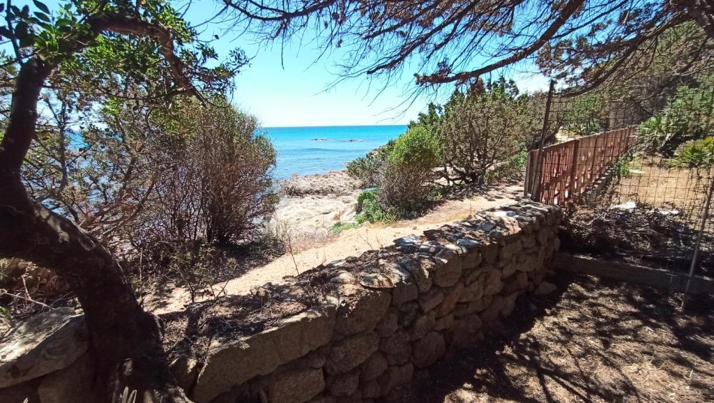 a stone wall next to a beach with the ocean at Villino Corallo Roby in Cala Liberotto
