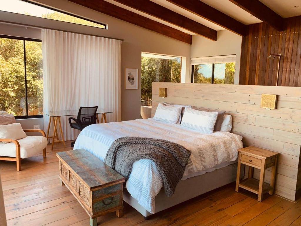 a bedroom with a bed and a chair and windows at Anastasis in Cape Town