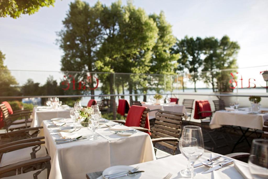 een groep tafels met witte tafelkleden en stoelen bij Hotel Kleines Meer in Waren