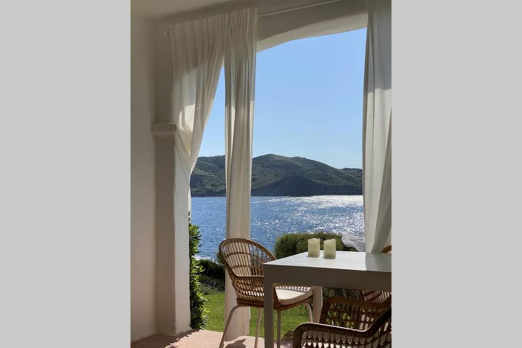 una sala da pranzo con tavolo e vista sull'acqua di Miravent Terraza y Jardin Frente al mar Menorca a Fornells