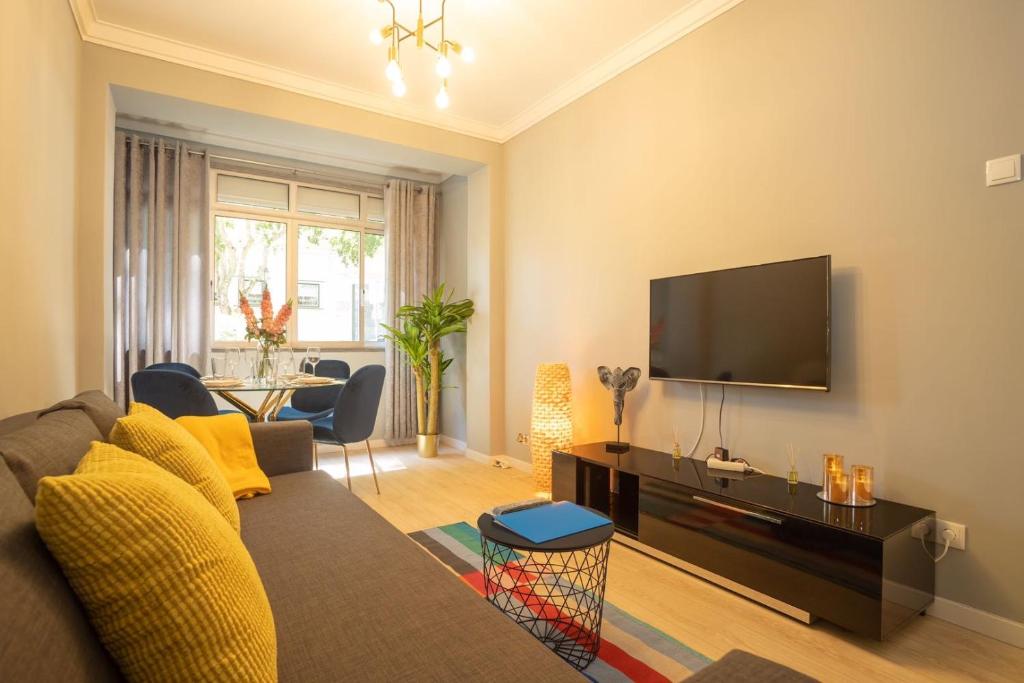 a living room with a couch and a flat screen tv at Golden Beach Apartment in Cascais