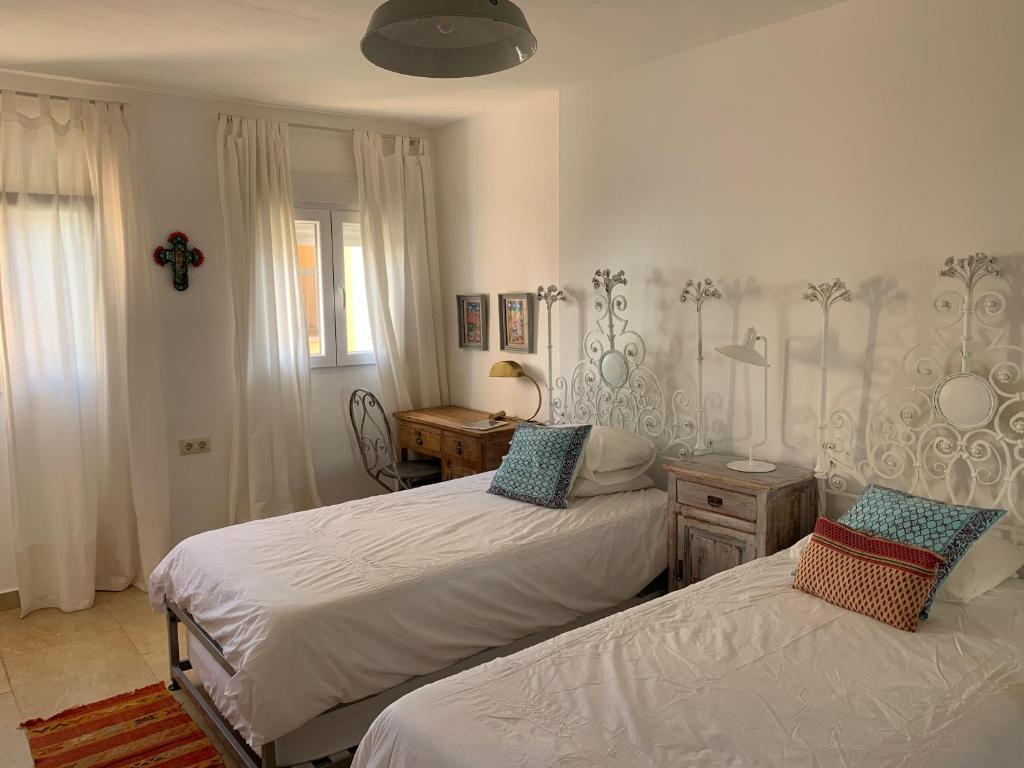 sypialnia z 2 łóżkami i krzyżem na ścianie w obiekcie CASA 4 HABITACIONES CON JARDIN 10 Pax w mieście Zahara de los Atunes