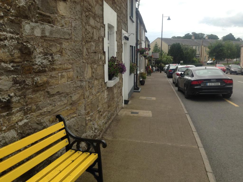 a yellow bench sitting on a sidewalk next to a building at Glaslough Ramblers Rest in Monaghan