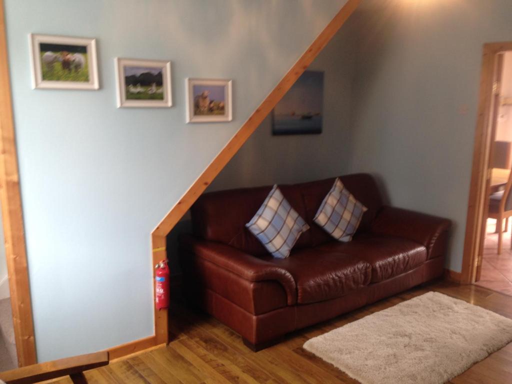 a brown leather couch sitting under a stair case at Glaslough Ramblers Rest in Monaghan