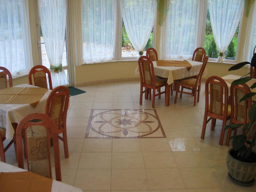 jadalnia ze stołami, krzesłami i oknami w obiekcie Hotel Pod Platanami w mieście Trzebnica