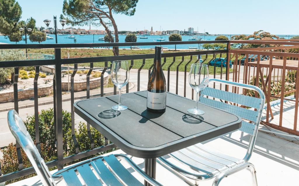 Villa Umag Seafront في أوماغ: طاولة مع كأسين وزجاجة من النبيذ