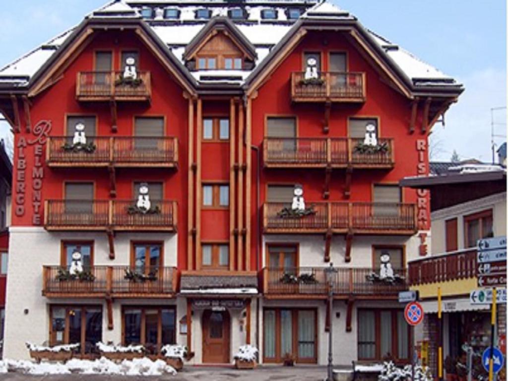 a large red building with balconies on a street at Hotel Belmonte in Roana