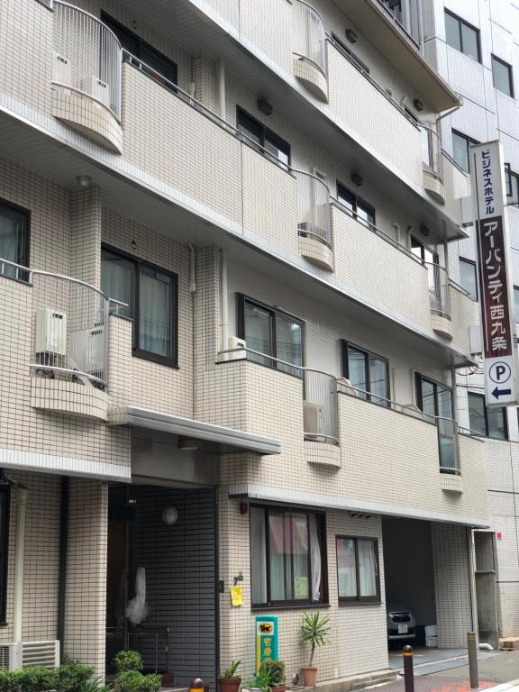een hoog gebouw met ramen en een straatbord bij Business Hotel Urbanty Nishikujo in Osaka