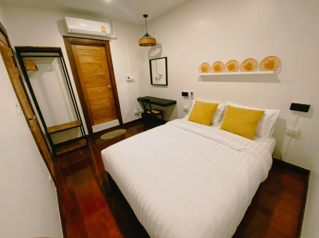 ein Schlafzimmer mit einem großen weißen Bett mit gelben Kissen in der Unterkunft บ้านในกาด-ที่พักน่าน โรงแรมน่าน เที่ยวน่าน in Nan