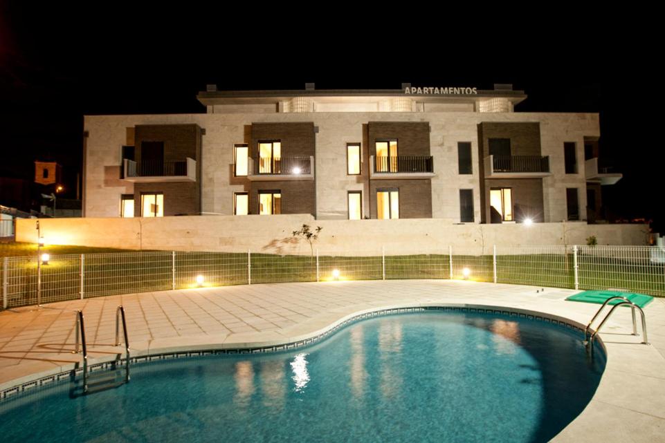 una piscina frente a un edificio por la noche en Costa Quebrada Apartamentos, en Soto de la Marina