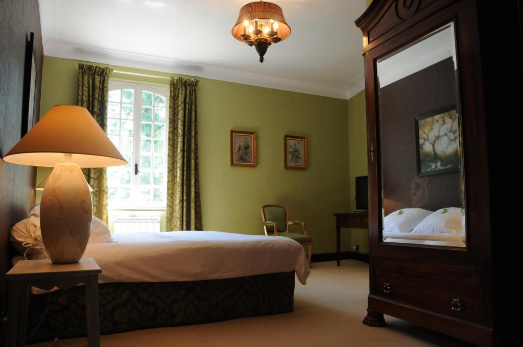 a bedroom with a bed and a lamp and a mirror at Hostellerie Restaurant Les Gorges de l'Aveyron in Bruniquel